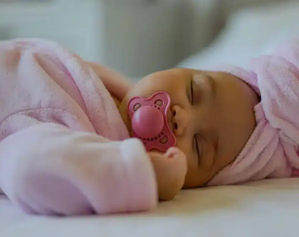 Danos causados pela chupeta2 Bebê recém-nascido tranquilo dormindo em traje rosa com chupeta. Início de danos causados pela chupeta
